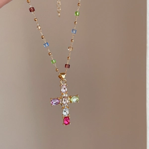 Détail du pendentif croix en or avec pierres précieuses colorées et diamants