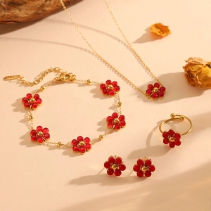 Detailed set of gold floral jewelry with red petals and cat-eye stones on warm background