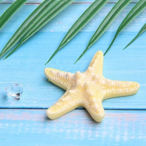 Realistic large yellow resin starfish figurine on blue and white wooden background
