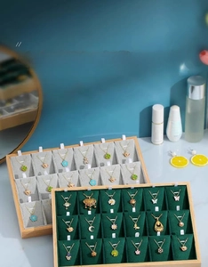 Close-up of an 18-slot bamboo jewelry display tray with grey and green velvet lining