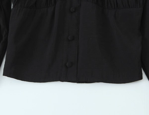 Détail de la blouse vintage noire avec fermeture à boutons et taille plissée élégante