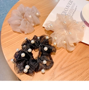 Detailed view of organza hair scrunchies with white pearls in black, pink and cream