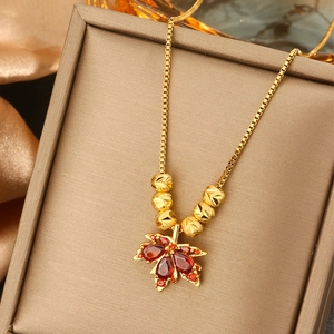 Detail of red gem maple leaf pendant on a gold box chain inside a jewelry box