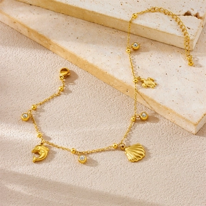 Gold stainless steel anklet featuring sea turtle dolphin and shell charms on stone background