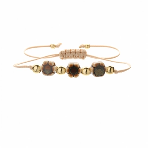Detail of bohemian ceramic flower beads and gold metal accents on adjustable braided bracelet