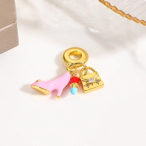 Detailed view of gold pendant with pink high heel, red lipstick, and luxury handbag charms
