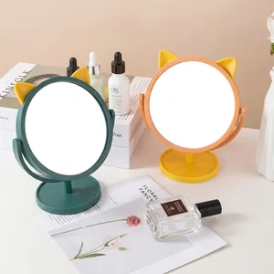 Rotating cat-ear desk mirrors with storage base in green and orange, modern home setup