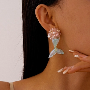 Dettaglio di orecchini a fiore in resina rosa e coda di sirena su modella femminile