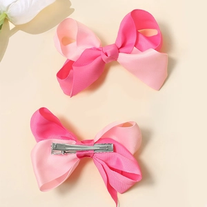 Close-up of pink grosgrain ribbon hair bows showing front side and metal alligator clips