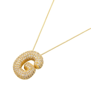 Macro detail of bubble letter G pendant with cubic zirconia inlay on a gold box chain