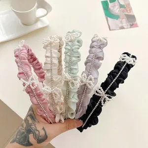 Detail showing satin pleated headbands with pearl bows and rhinestone embellishments