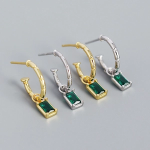 Detail view of bamboo texture earrings with emerald green rectangular gemstone charms