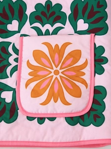 Close-up of pink fabric jacket with orange flower patterns and detailed green stitching