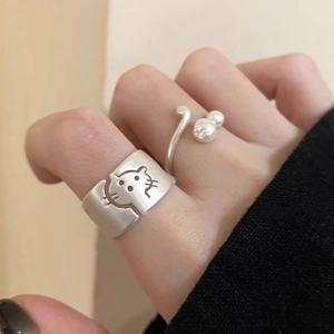 Detail of matte silver cat-themed rings featuring a cute face and pearl tail design