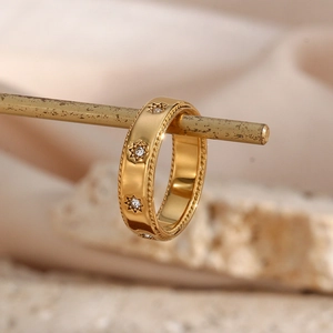 Gros plan sur une bague en acier doré avec motif étoile, pierres zircons et bord ciselé