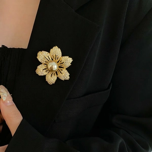 Elegant gold flower brooch with sparkling cubic zirconia petals and a center pearl