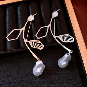 Detailed view of gold and silver vintage leaf brooches with baroque pearls in a jewelry box