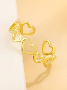 Dettaglio dell'anello aperto dorato con forme a cuore cavo e finitura in metallo lucido