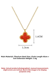 Macro shot of gold clover pendant with red stones and measurements for sizing details