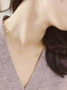 Macro detail of 18K gold plated silver necklace with clover charms and zircons