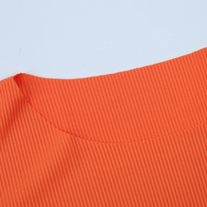 Detailed close-up of orange ribbed knit crewneck and stitching on a slim fit dress