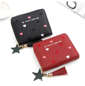Detail of short leather wallets with heart patterns, star charms and decorative tassels