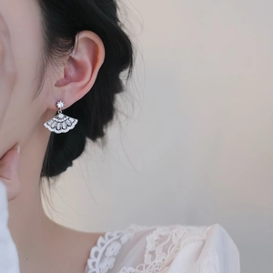 Close-up of fan-shaped silver earrings with sparkling zircon on a female model
