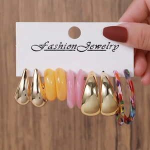 Detail of C-shaped resin earrings in colorful patterns and gold finish on display card