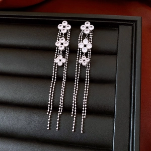 Detailed view of silver flower tassel earrings with clear zircons on black leather display