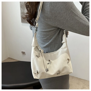 Close-up of white crossbody bag featuring silver butterfly charms and adjustable strap