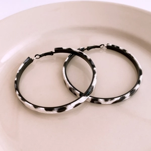 Detailed close-up of leopard pattern hoop earrings with zebra print on a beige display plate