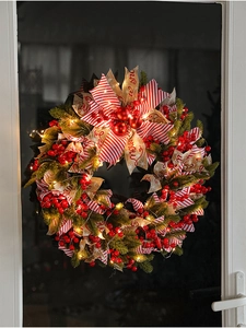 Detail of 50cm Christmas wreath with LED lights, red berries and ribbons on a glass door