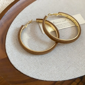 Close-up of brown flocked velvet circular hoop earrings with golden metal details