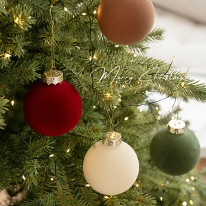 Boules de Noël floquées en velours bordeaux, vert et marron sur un sapin de fête