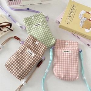 Detail of plaid canvas mini shoulder bags in green, brown and pink with adjustable straps