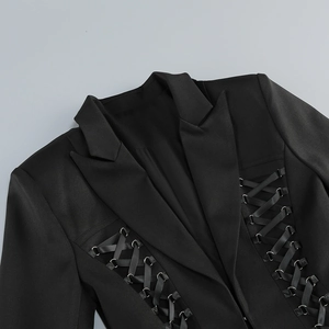 Detailed shot of the criss-cross lace-up waist design on a black blazer dress