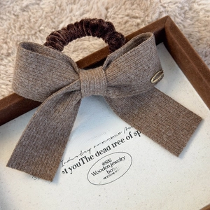 Close-up of brown knit bow hair scrunchie with metal detail on a decorative tray