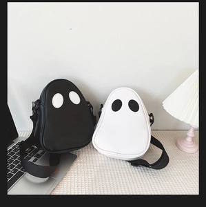 Detail of cute ghost-shaped PU leather crossbody bags in black and white with smooth texture