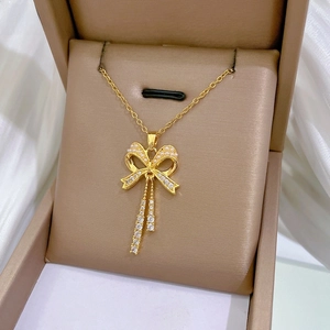 Macro shot of gold bow tassel necklace with micro-pave zircons in a premium gift box
