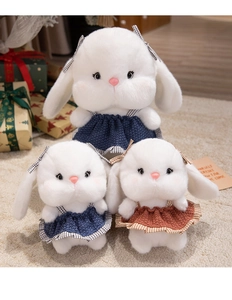 Detailed view of white plush rabbit dolls wearing knit dresses in festive holiday setting