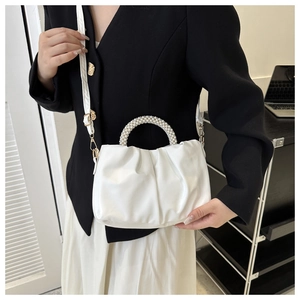 Detail of white pleated cloud bag featuring premium faux leather and elegant pearl handle