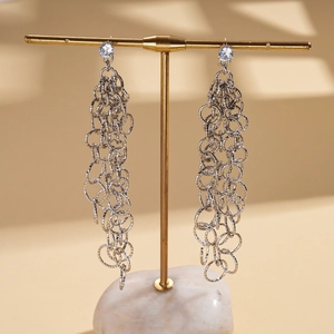 Détail de boucles d'oreilles argentées à pampilles avec cercles géométriques et zircon