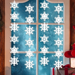 White Christmas hanging snowflake garland ornaments displayed against a frosty window glass