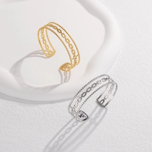 Detail view of multi-layer C-shaped chain bangles in gold and silver stainless steel