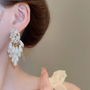 Detail of drop earrings with white pearls and sparkling crystals on gold alloy base