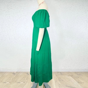 Detail of emerald green off-shoulder maxi dress showing elastic puff sleeves and tiered skirt
