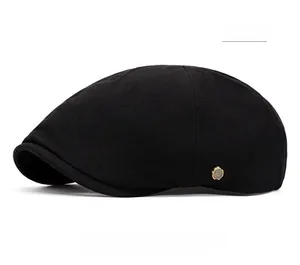Détail de la casquette plate noire avec badge métallique W en bronze sur coton sergé
