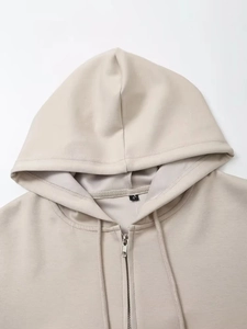 Dettaglio ravvicinato della scollatura e del tessuto della felpa beige con zip
