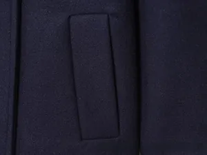 Detailed macro view of the rectangular pocket on a dark blue wool double-breasted coat