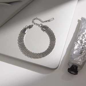 Silver multilayer stainless steel Cuban chain bracelet on a sleek laptop surface